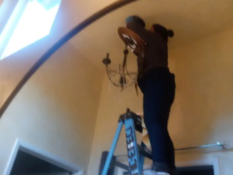 Electrician installing a chandelier in a Lynwood residence